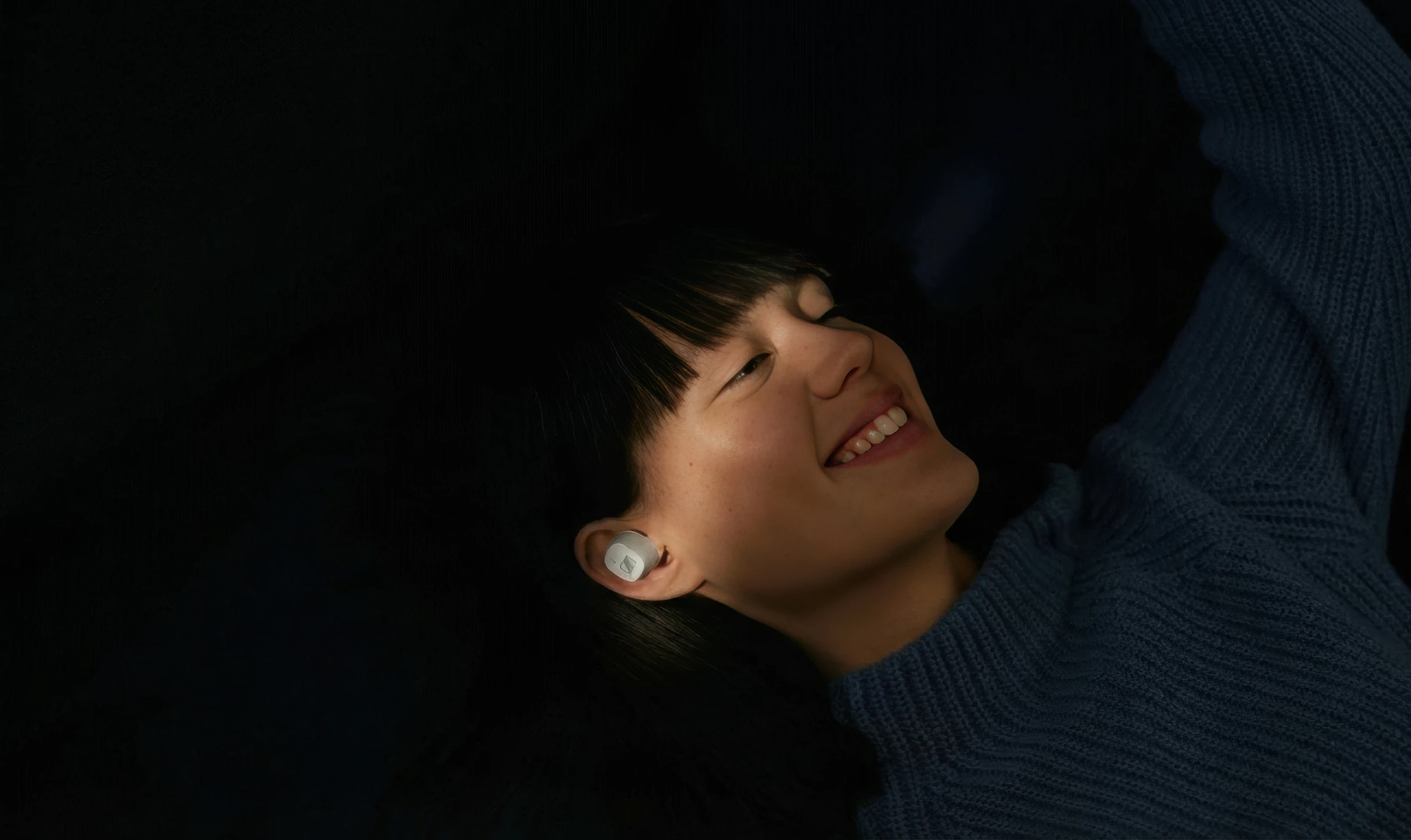 Person relaxing with earbuds, smiling
